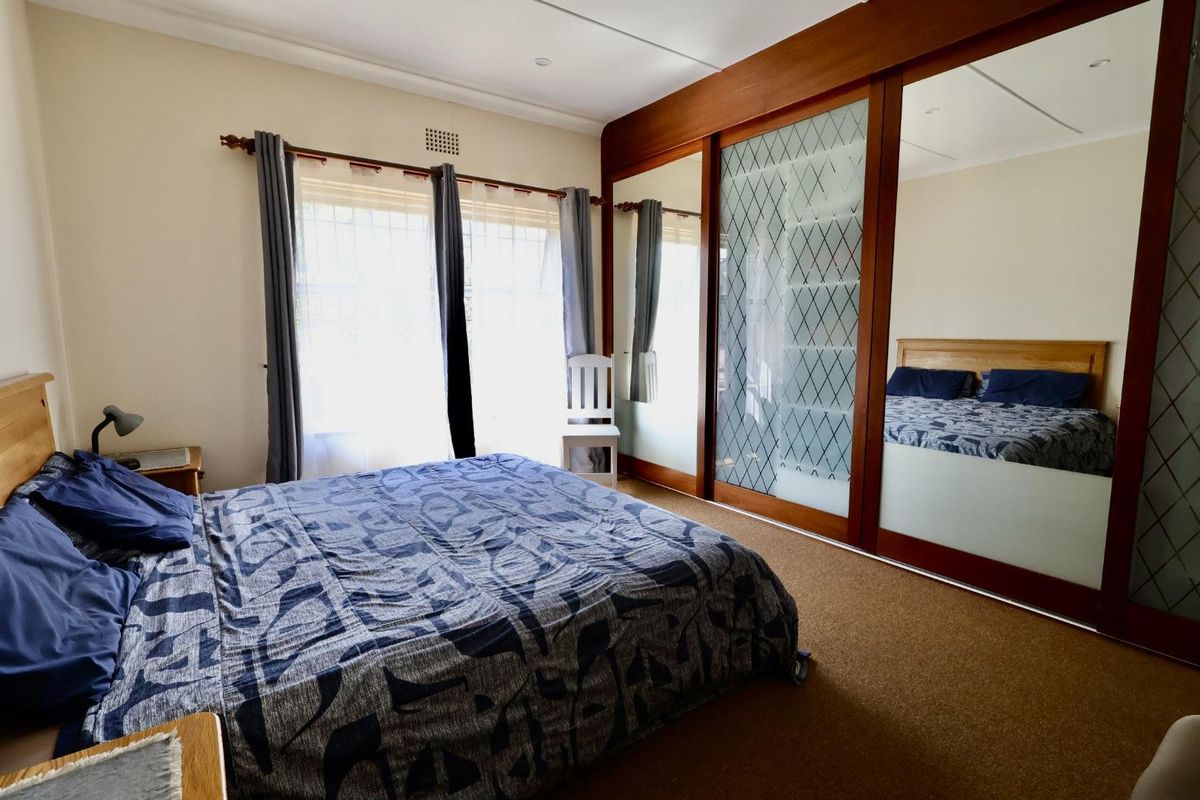 A bedroom featuring carpeted flooring and a large built-in wardrobe with mirrored and frosted glass sliding doors.