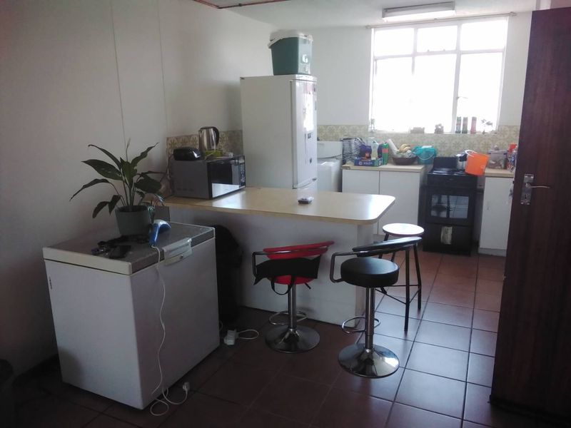 A functional kitchen area featuring tiled flooring, a built-in breakfast bar, and a tiled backsplash, offering a practical layout for daily use.