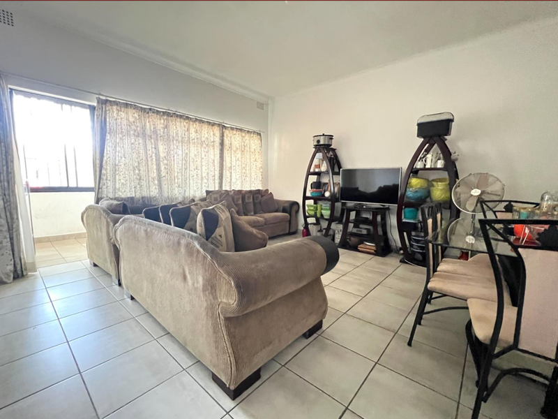 Spacious living area featuring neutral tiled flooring and large sliding glass doors that provide access to an outdoor balcony area.
