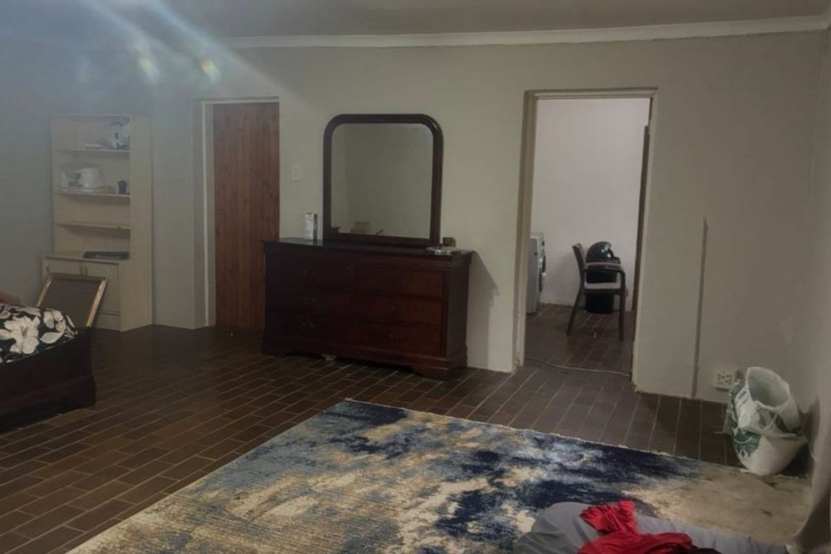 A spacious bedroom featuring tiled flooring, built-in shelving, and direct access to an adjoining utility or laundry area.