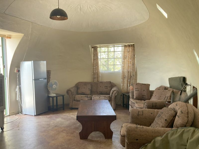 A unique living area featuring a distinctive domed ceiling and concrete flooring, offering a rustic architectural aesthetic with potential for modern interior updates.