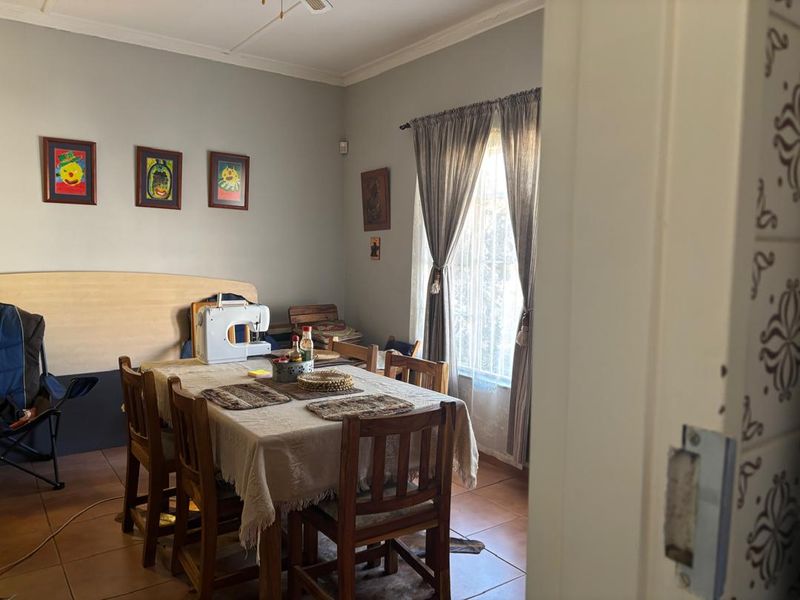 A functional dining room featuring tiled flooring and natural light through a window with curtain rails.