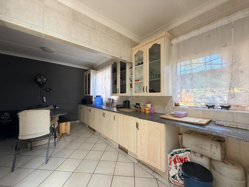 A functional kitchen featuring laminate cabinetry, tiled backsplash, and tiled flooring, offering a practical layout with ample storage space.
