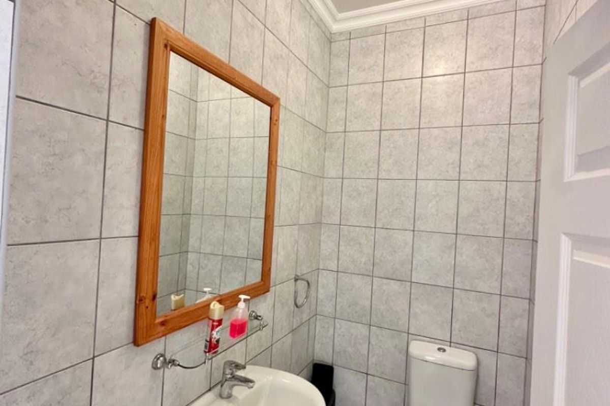 A compact bathroom featuring floor-to-ceiling wall tiles, a wall-mounted basin, and a standard toilet.