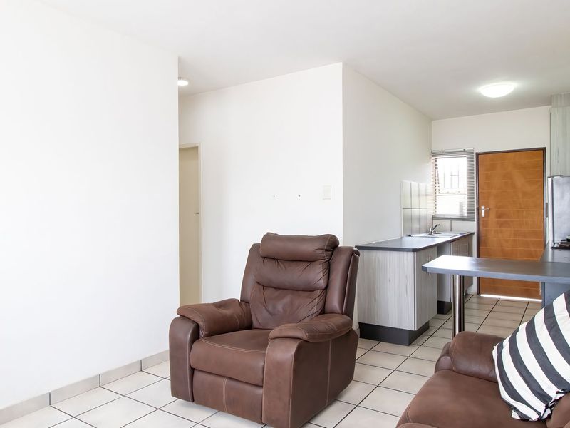 Open plan living area featuring tiled flooring and a functional kitchen space with built-in cabinetry and countertop.