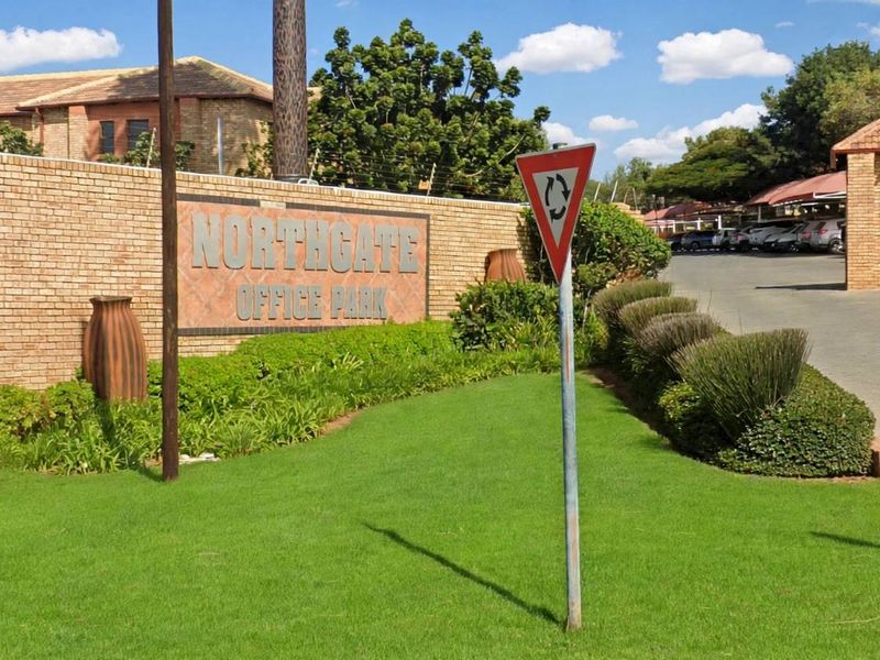 Entrance view of Northgate Office Park featuring a brick boundary wall, landscaped garden, and a secure gated access point.