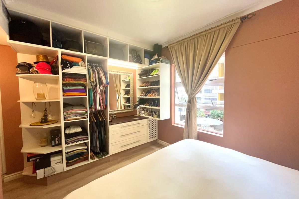 Bedroom featuring extensive built-in floor-to-ceiling shelving and cabinetry with integrated vanity mirror and storage drawers.
