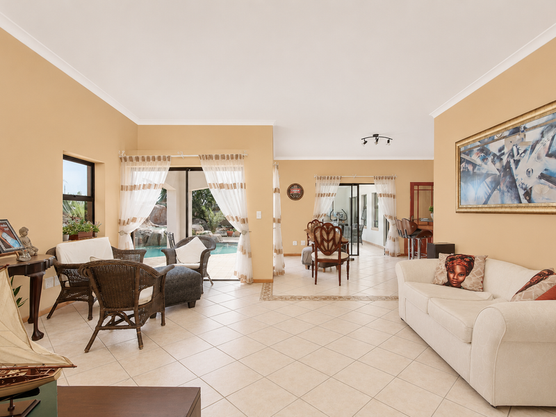 Spacious open-plan living area featuring tiled floors, neutral walls, and seamless flow to the outdoor pool area through large sliding glass doors.