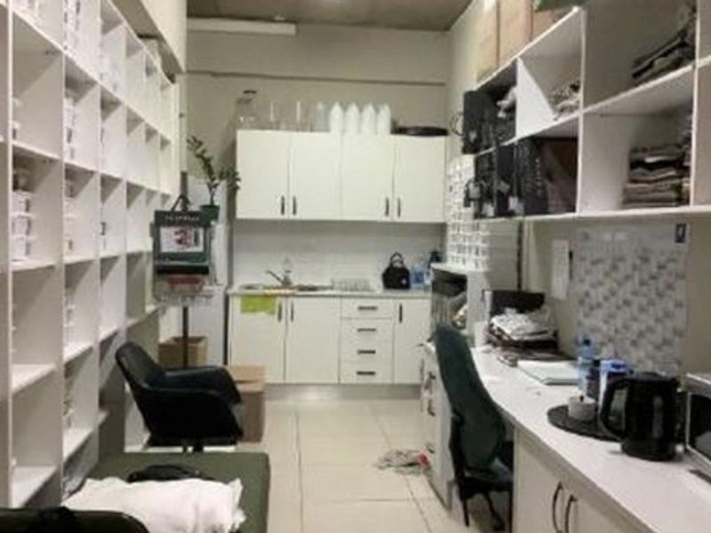 A functional scullery or utility area featuring extensive built-in cabinetry, open shelving, and a stainless steel sink, suitable for storage and preparation.