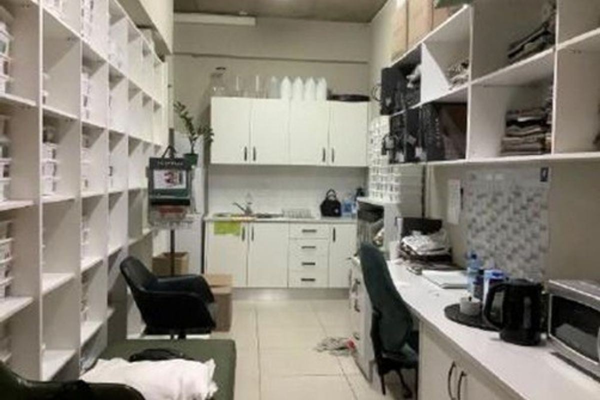 A functional scullery or utility area featuring extensive built-in cabinetry, open shelving, and a stainless steel sink, suitable for storage and preparation.