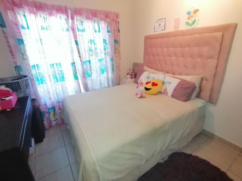 A standard bedroom featuring tiled flooring and a window with curtains.