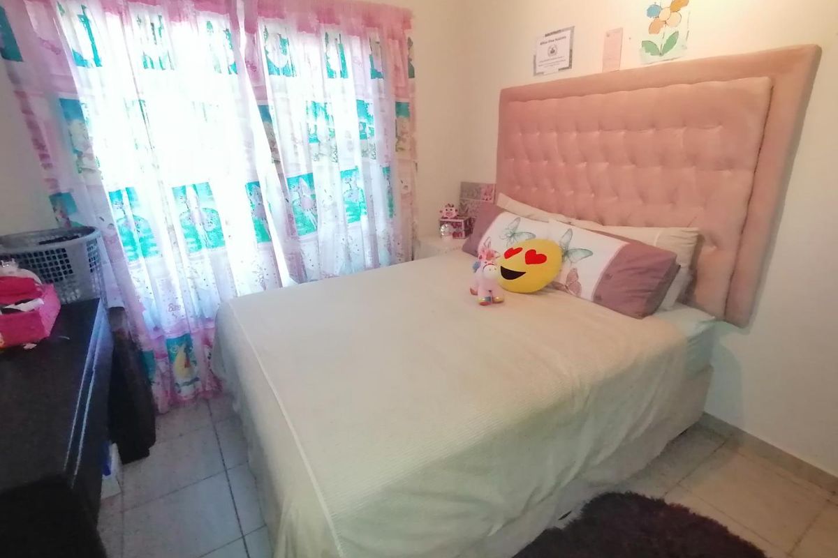 A standard bedroom featuring tiled flooring and a window with curtains.