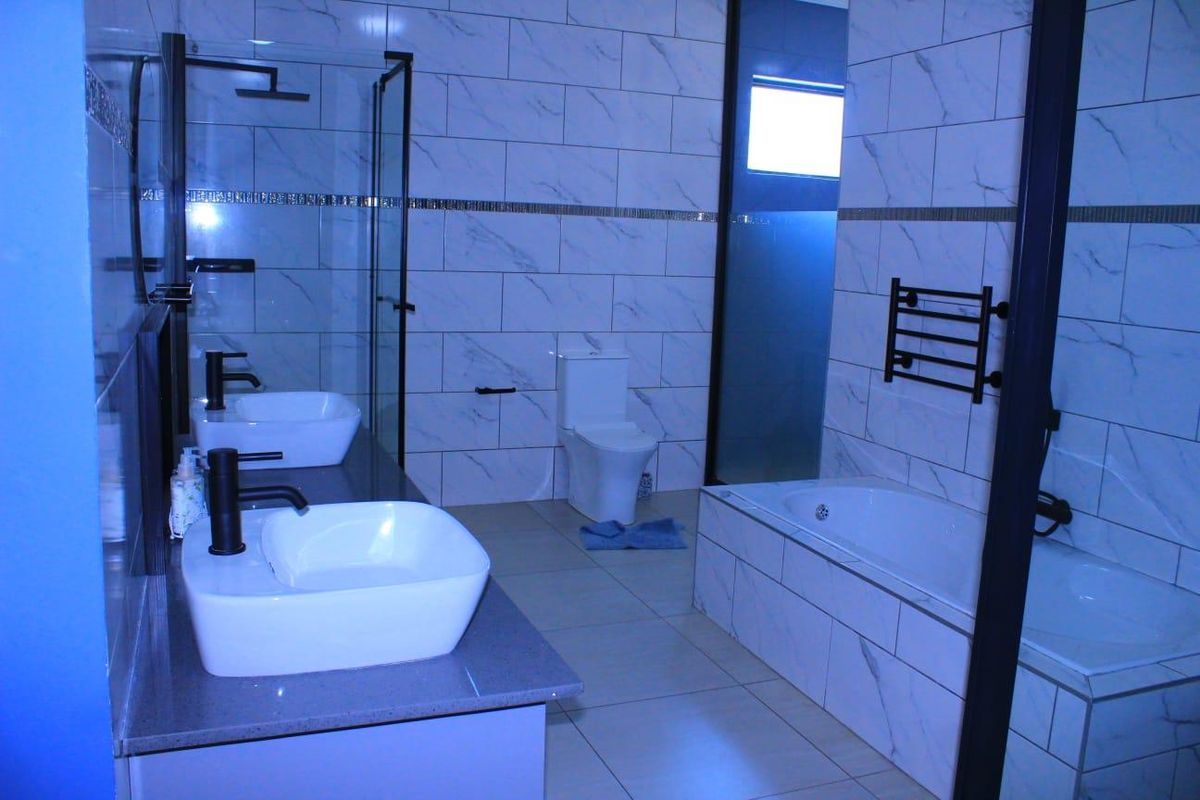 Modern bathroom featuring a double vanity with vessel sinks, a glass-enclosed shower, a built-in bathtub, and contemporary marble-look wall tiling.