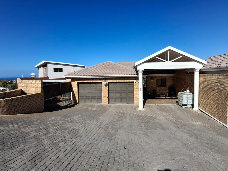 Front view of the property featuring a double garage, a covered carport, and a spacious brick-paved driveway.