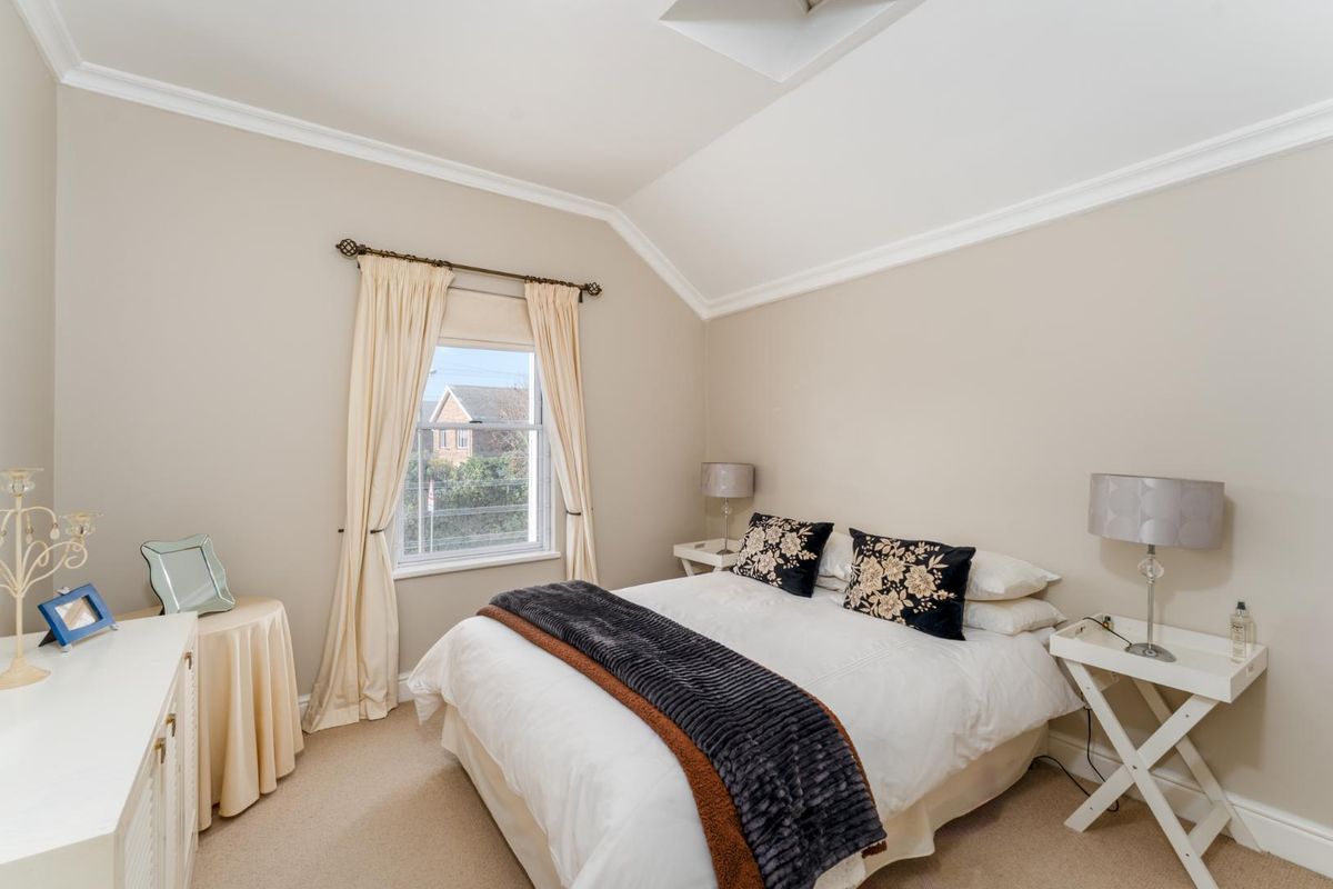 A well-maintained bedroom featuring a vaulted ceiling, neutral wall tones, and carpeted flooring, providing a bright and comfortable living space.