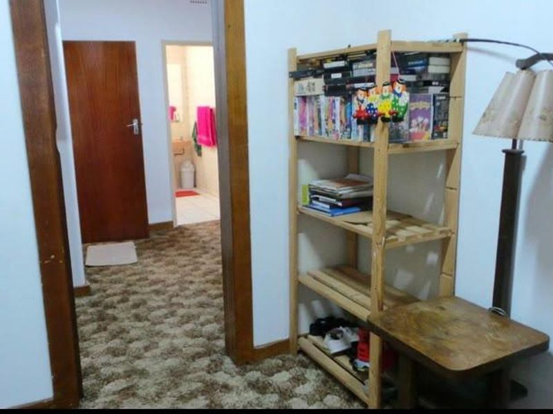 A residential hallway featuring wooden door frames and carpeted flooring, providing access to adjacent rooms including a bathroom.