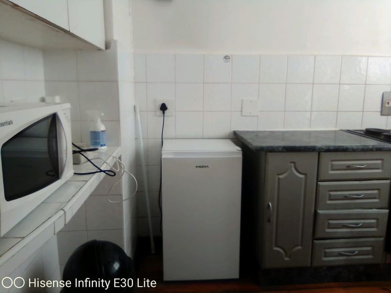 A compact kitchen area featuring tiled splashbacks, laminate countertops, and built-in cabinetry, providing essential food preparation space.