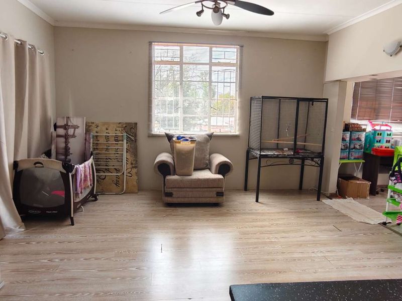 Spacious living area featuring laminate flooring, a ceiling fan, and large windows providing natural light, with direct access to an outdoor patio area.