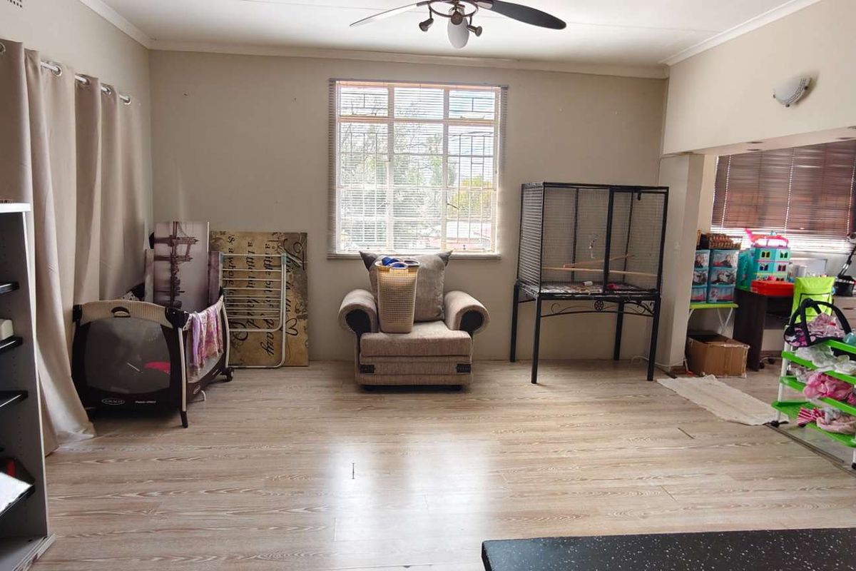 Spacious living area featuring laminate flooring, a ceiling fan, and large windows providing natural light, with direct access to an outdoor patio area.