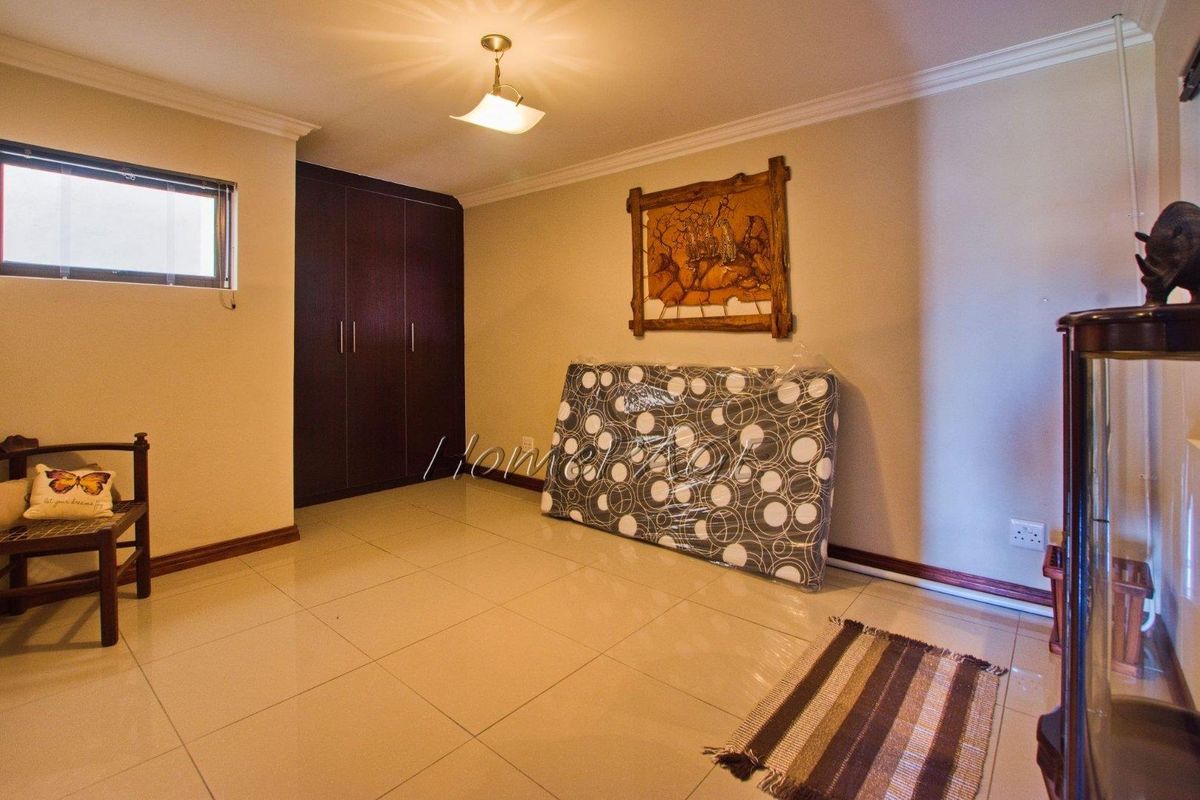 A bedroom featuring tiled flooring, built-in cupboards, and neutral wall finishes, offering a clean and functional space ready for personalization.