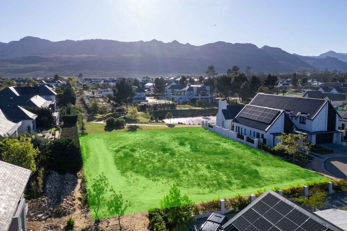 An aerial view of a vacant residential plot in a developed estate, highlighting the buildable area with mountain views.
