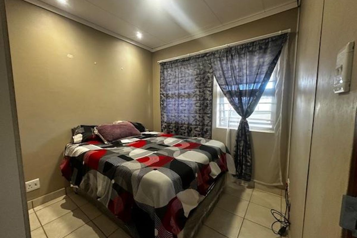 A compact bedroom featuring tiled flooring, a window with fitted curtains, and recessed ceiling lighting.