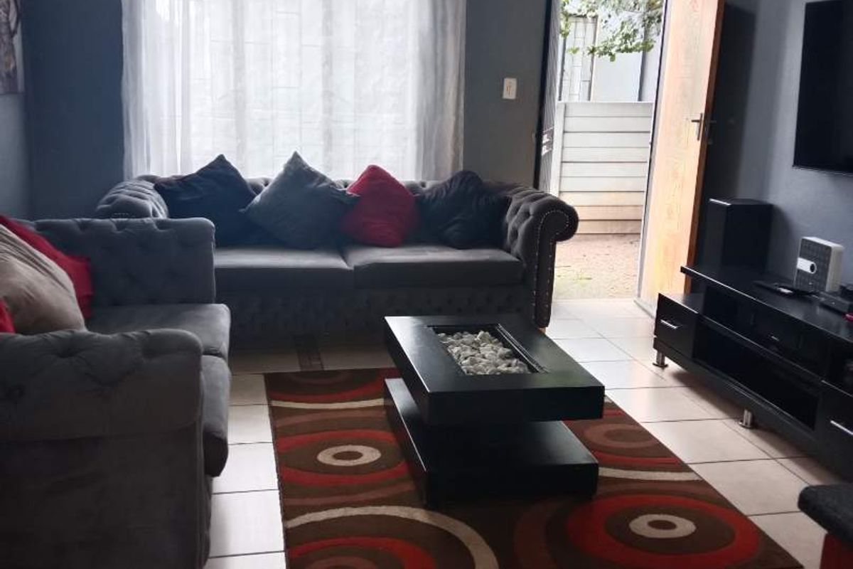A living room featuring tiled flooring, recessed ceiling lighting, and direct access to an outdoor area through a side door.