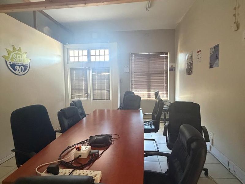 A functional office space featuring tiled flooring, timber-framed partition detailing, and venetian blinds, suitable for a professional meeting or workspace environment.