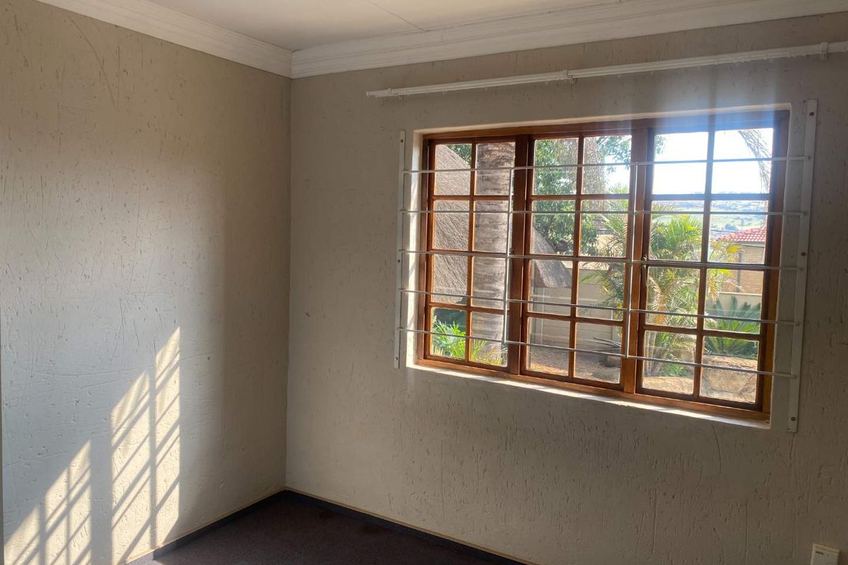 A vacant bedroom featuring textured walls, crown molding, and a wooden window frame with external security bars.