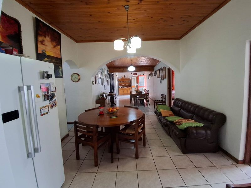 Open plan living and dining area featuring ceramic floor tiles and a timber tongue and groove ceiling with an arched transition between spaces.