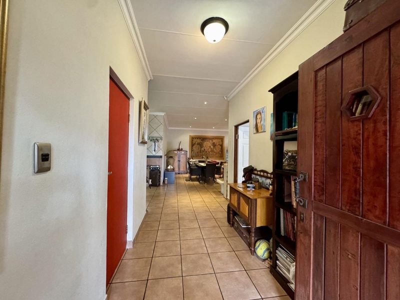 A tiled hallway featuring cove cornicing and a flush mount ceiling light, providing access to the main living areas of the home.