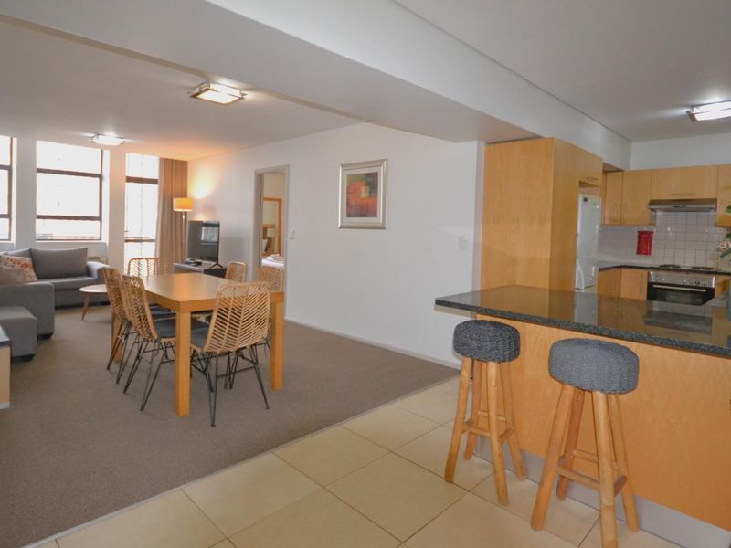 Open-plan living and dining area featuring a functional kitchen with granite countertops, built-in cabinetry, and integrated appliances.
