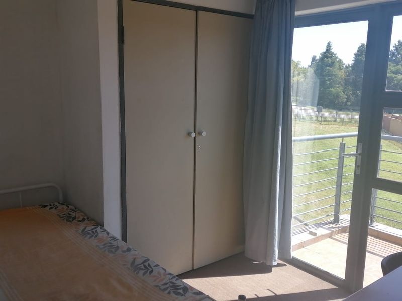 A bedroom featuring a built-in wardrobe, carpeted flooring, and direct access to a private balcony through a sliding glass door.