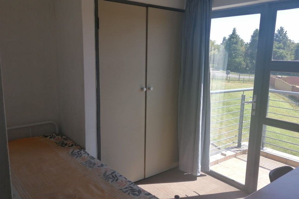 A bedroom featuring a built-in wardrobe, carpeted flooring, and direct access to a private balcony through a sliding glass door.