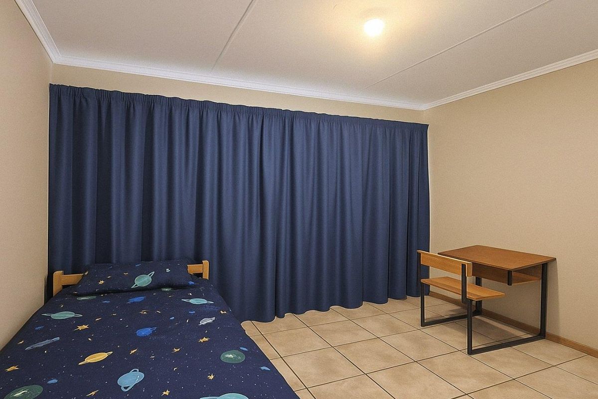 A functional bedroom featuring neutral wall tones, tiled flooring, and full-length curtains covering the window area.