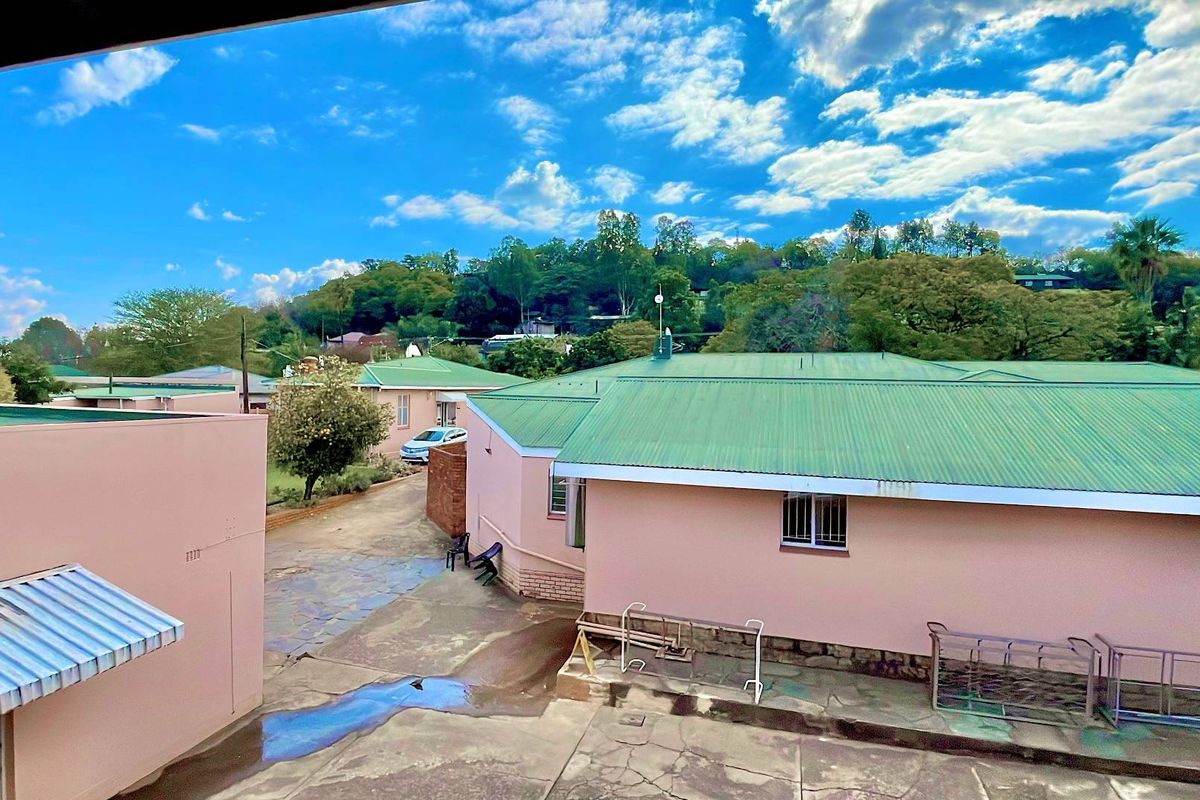 Elevated view of the property grounds featuring multiple buildings with green metal roofing and paved courtyard areas.