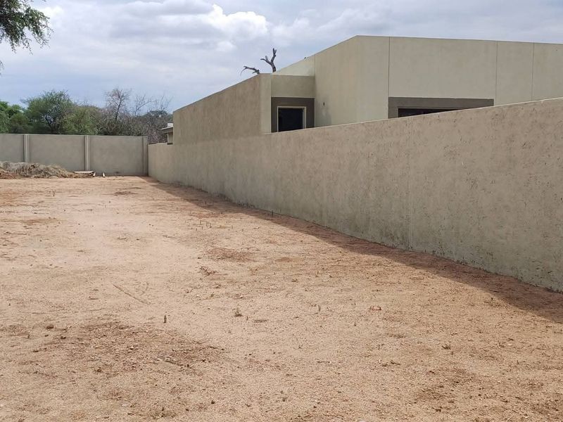 A vacant residential plot featuring a secure precast concrete boundary wall and cleared ground, ready for development.