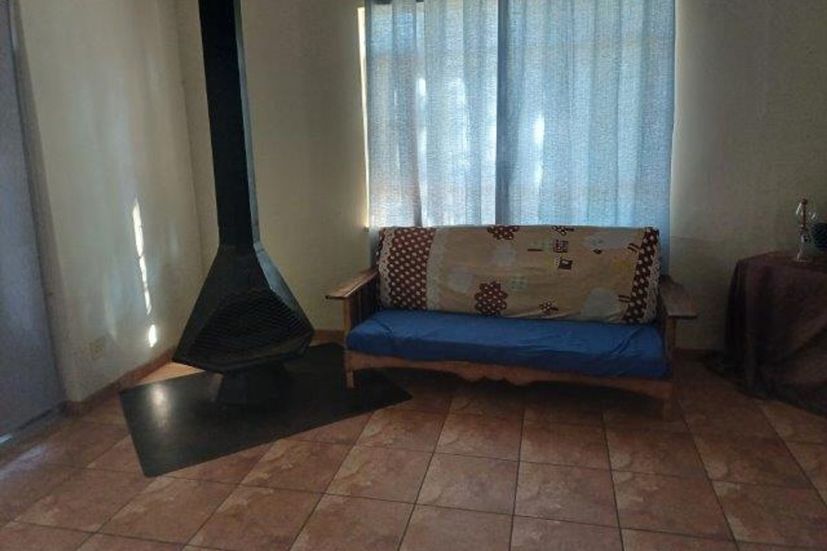 Living room featuring a freestanding fireplace and tiled flooring, providing a functional space with potential for modern updates.