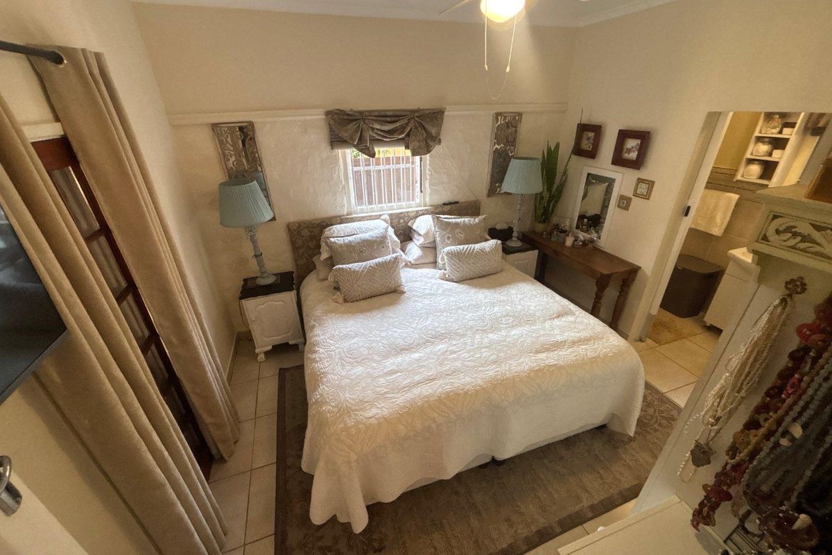 A cozy bedroom featuring tiled flooring, a ceiling fan, and an adjoining en-suite bathroom, providing a functional and comfortable living space.
