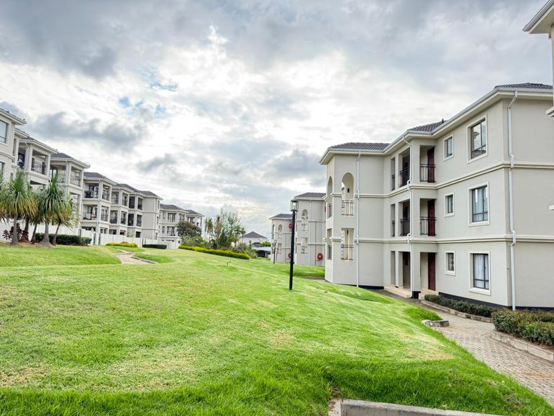 A view of the apartment complex grounds featuring well-maintained lawns, paved pathways, and multi-story residential buildings with balconies.