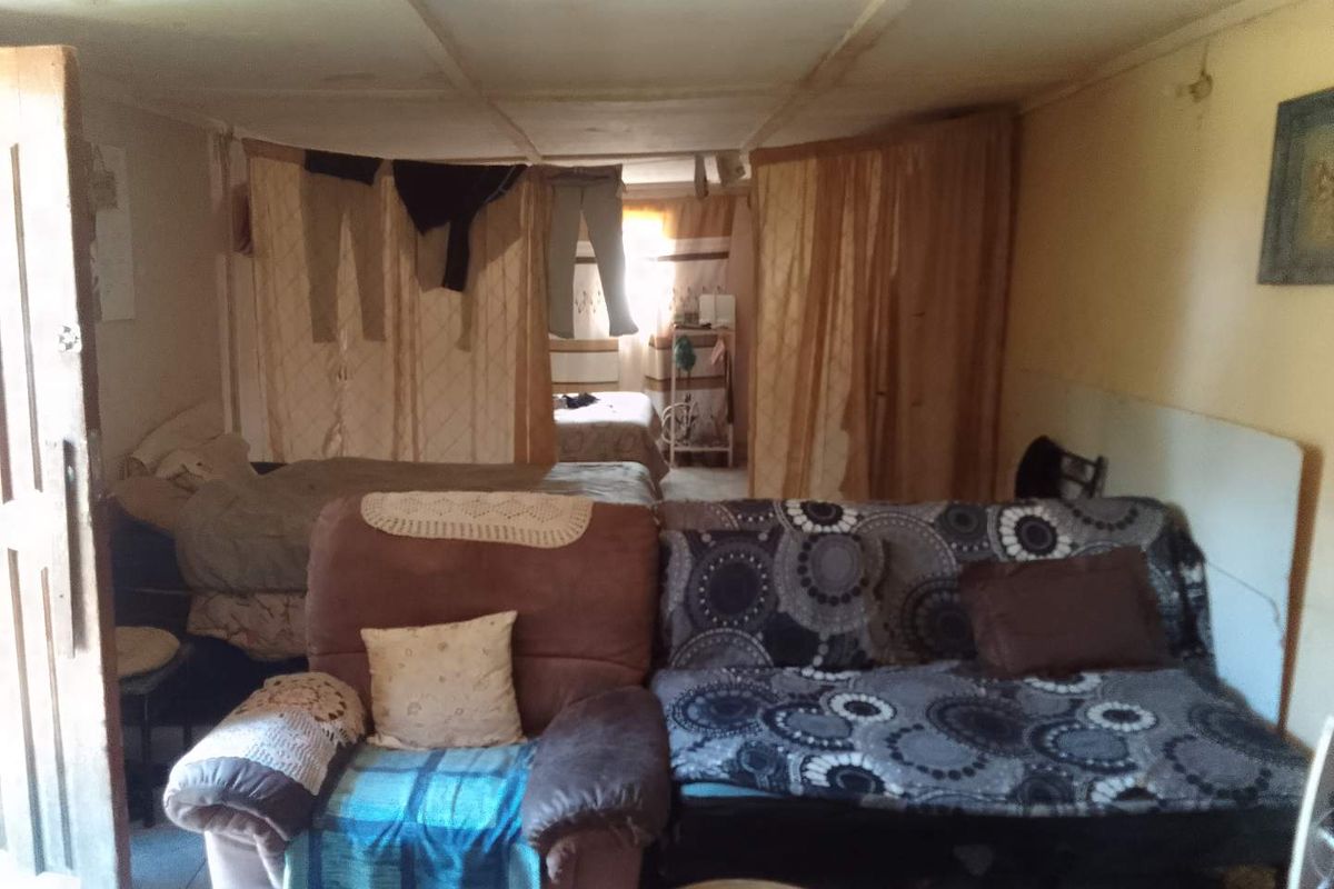 An interior view of a multi-purpose living and sleeping area featuring basic finishes and a partitioned layout.