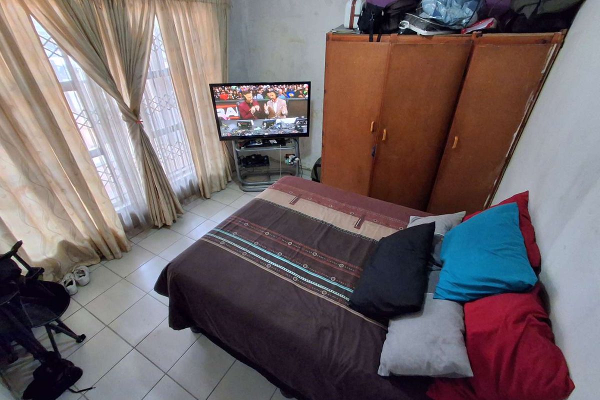 A bedroom featuring tiled flooring, large windows with curtains, and built-in storage cabinetry.