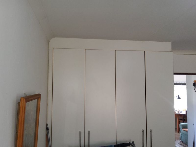 A bedroom featuring white built-in cupboards with modern handles, providing ample storage space.