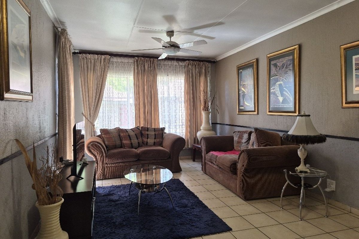 A comfortable living room featuring tiled flooring, a ceiling fan, and neutral wall tones, providing a functional and well-lit space for relaxation.