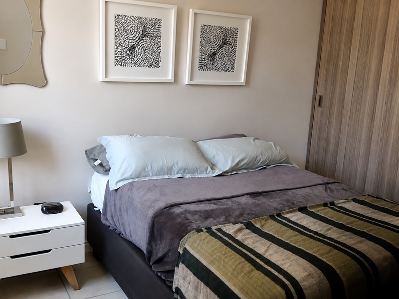 A well-maintained bedroom featuring neutral wall tones and a functional built-in wardrobe with wood-finish sliding doors.
