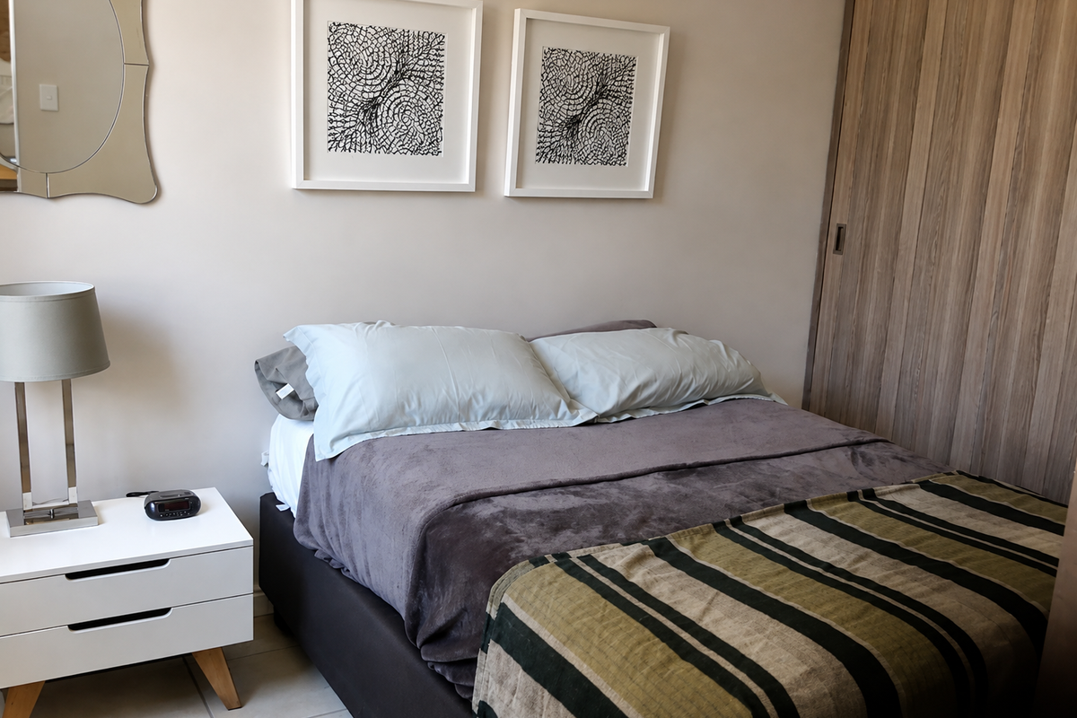 A well-maintained bedroom featuring neutral wall tones and a functional built-in wardrobe with wood-finish sliding doors.
