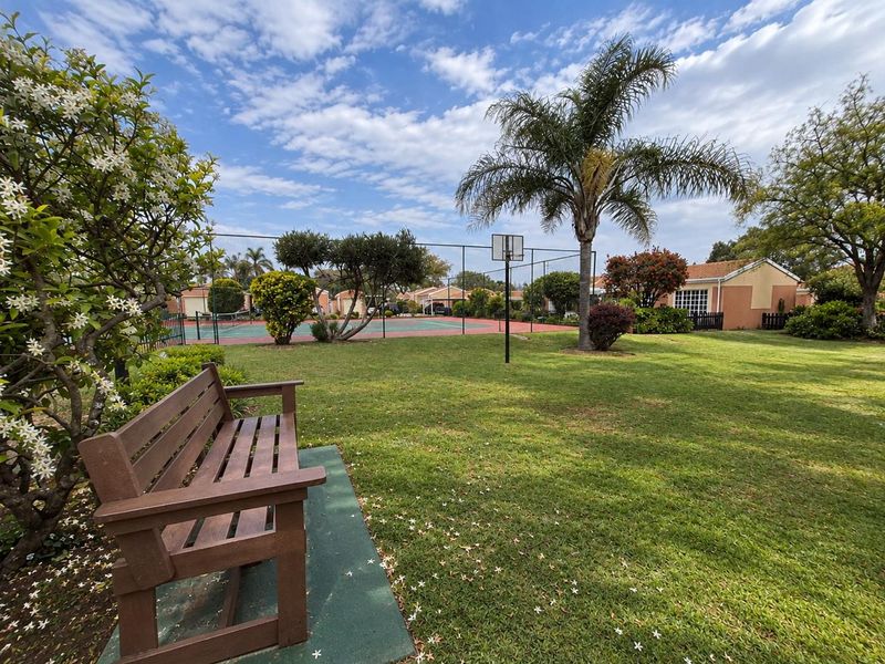 Well-maintained communal sports facility featuring a tennis court, basketball hoop, and surrounding landscaped garden area within the townhouse complex.