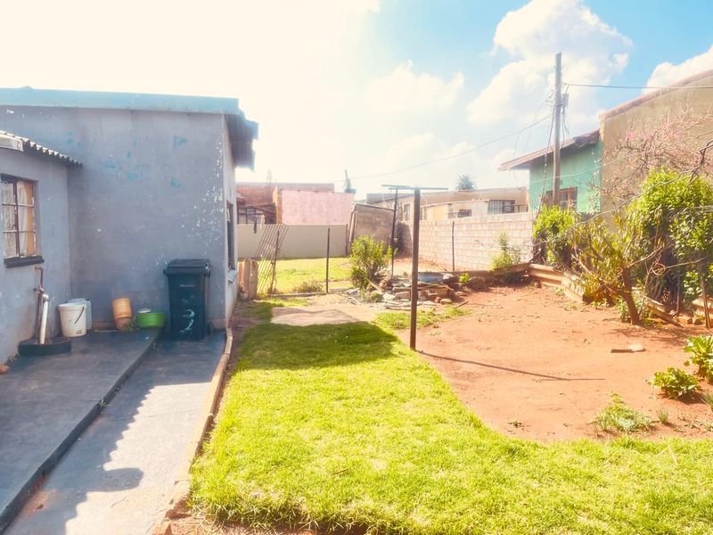Rear garden area featuring a concrete path, perimeter wall, and washing line, with potential for landscaping and exterior maintenance.