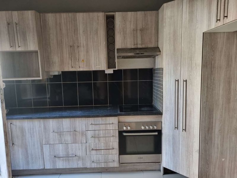 A functional kitchen featuring wood-look cabinetry, dark countertops, a tiled backsplash, and integrated Bosch oven and hob.
