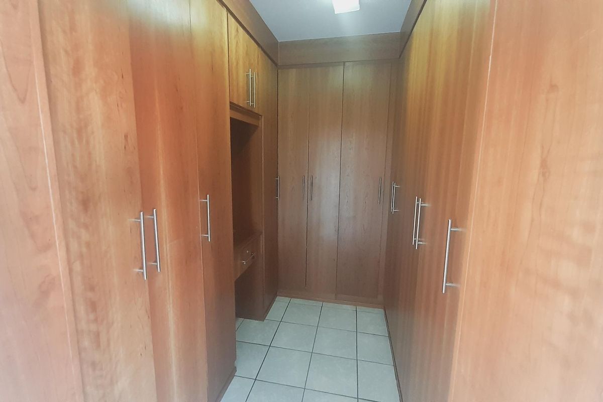 A walk-in closet featuring extensive floor-to-ceiling wooden cabinetry with integrated storage and a small built-in vanity area.